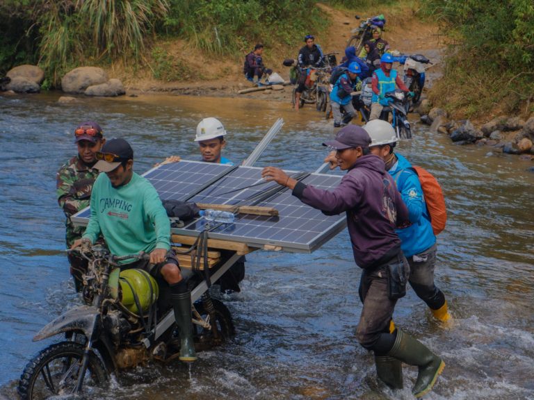 Petugas PLN Membawa Perangkat Supersun Melewati Sungai Menuju Dusun Palandoan Kecamatan Seko Luwu Utara Sulawesi selatan.